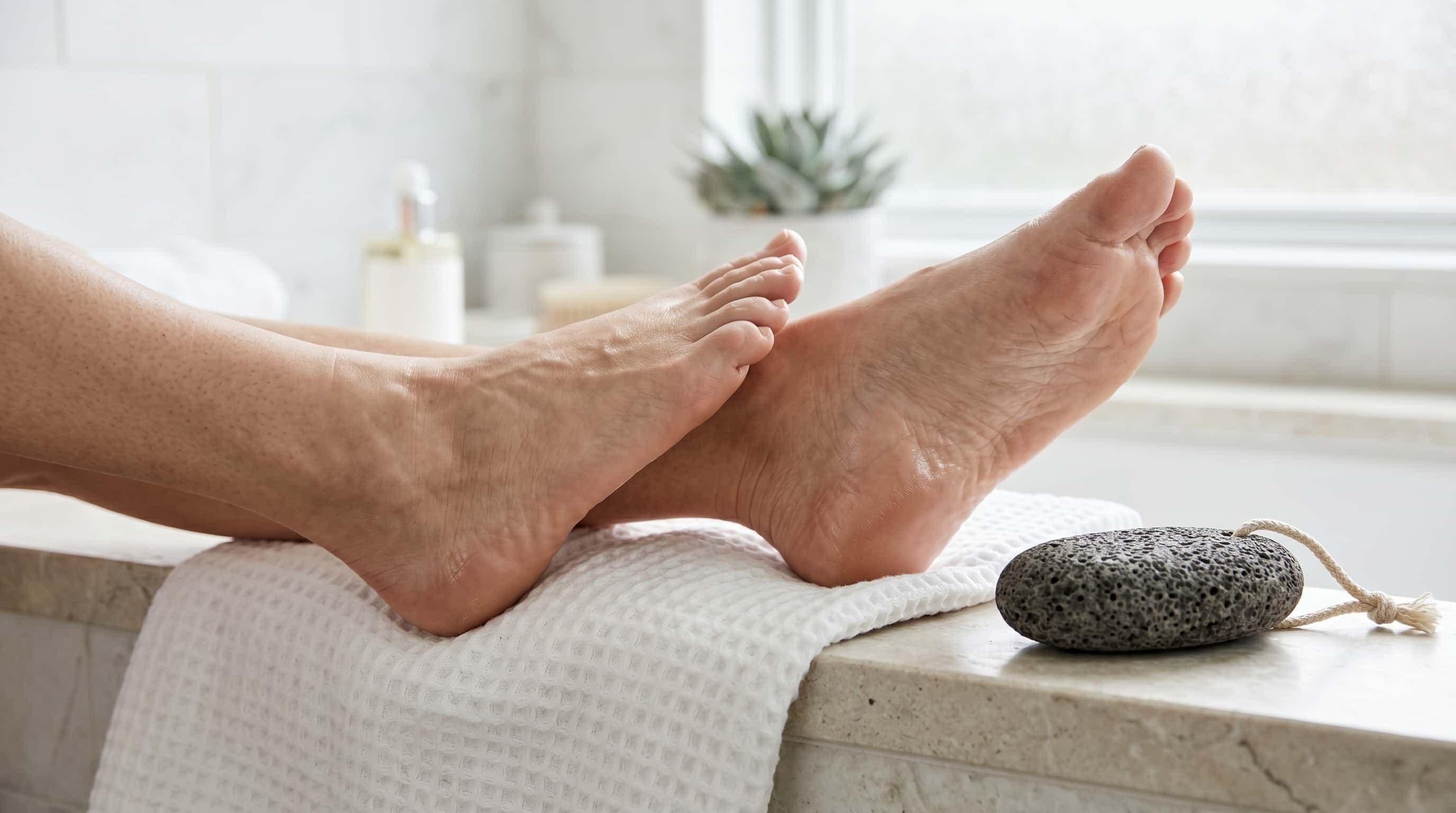A natural pumice stone beside heels and a towel in a bright foot-care setting.